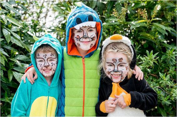 Three onesie-wearing youngsters get into the snow leopard spirit thanks to the zoo's face painting team!